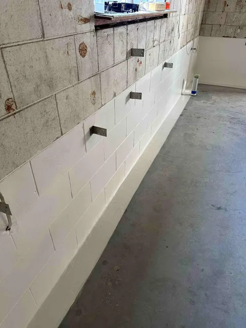 Waterproofing coating applied to lower section of concrete block basement wall