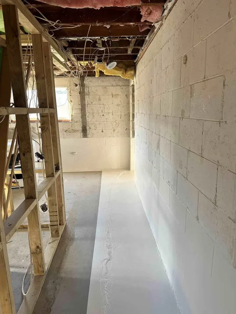 Concrete block basement with waterproofing applied to wall and floor during renovation